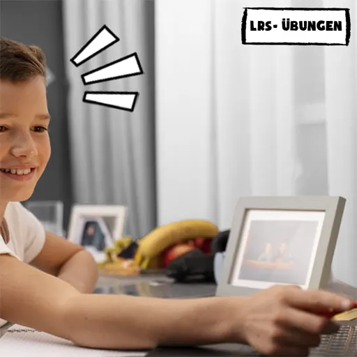 Junge zeigt lächelnd mit seiner Hand, in der er einen Stift hält, auf das Displays eines Laptops, auf dem noch ein Smartphone steht.