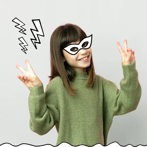Mädchen mit stilisierter Comichelden-Maske zeigt mit beiden Händen das Peace-Zeichen und lacht.